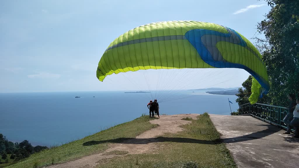 Pilot dan penumpang tandem bersiap lepas landas di Puncak Langkisau dengan layar terkembang